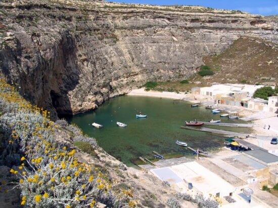 Barques et bâtiments au bord de l’Inland Sea sous les falaises de Dwejra